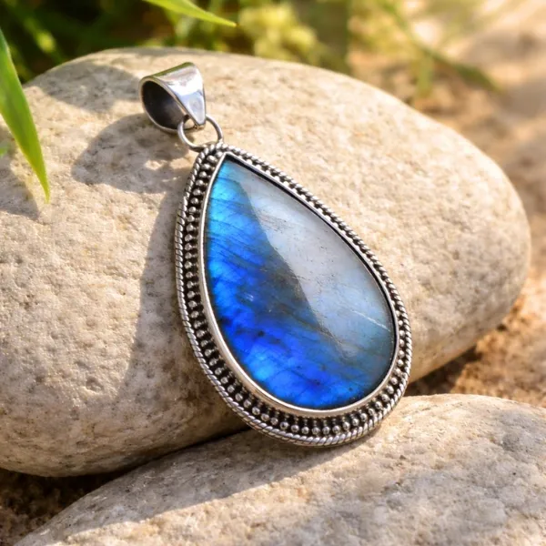Labradorite Gemstone Pendant in 925 Sterling Silver - Teardrop Shape with Brilliant Blue Flash on Natural Stone Background
