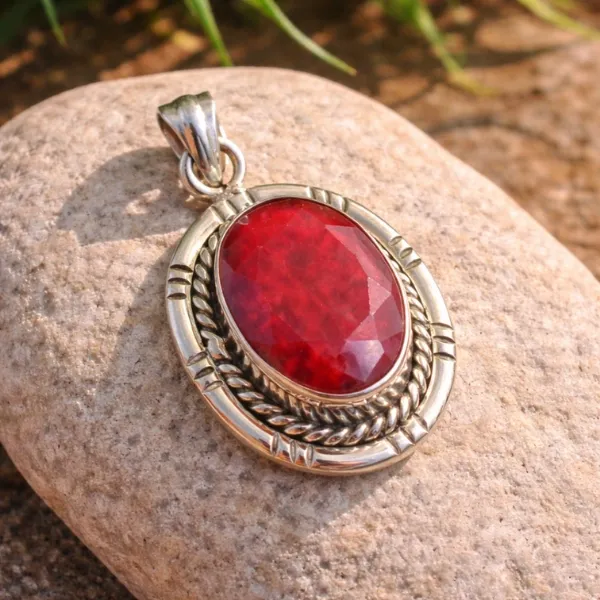 Kashmir Ruby Pendant in 925 Sterling Silver - Oval Red Manik Stone with Ornate Twisted Rope Border on Sandy Background